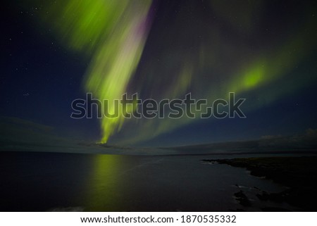 Aurora borealis against the line of the sea and the night sky
