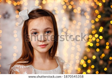 Portrait of a girl on the background of bokeh lights garlands. The child is enjoying Christmas. Portrait of a girl with a Christmas mood.