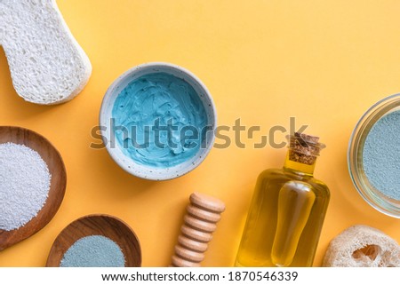 Natural cosmetic products for spa beauty routine on yellow background.
Bath salt, clay, loofah, olive oil, massage roller and pumice stone