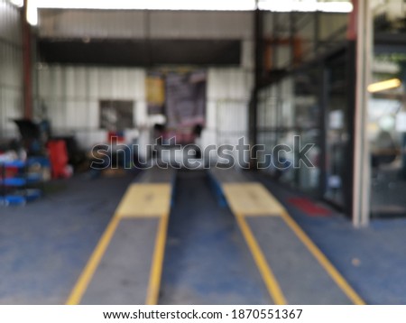 blur focus of alignment machine at car workshop.Image has grain or blurry or noise and soft focus.Car under repair on hoist at service station
