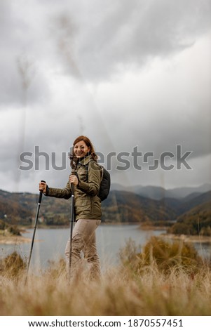Smiling woman looking at camera, posing for picture with two sticks.