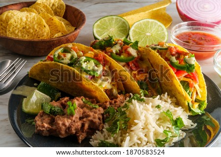 Mexican beef tacos with rice refried beans tortilla chips and various toppings Royalty-Free Stock Photo #1870583524