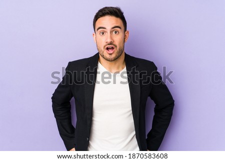 Young caucasian man isolated on purple background being shocked because of something she has seen. Royalty-Free Stock Photo #1870583608