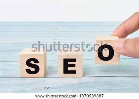 The hand puts the wooden cubes with the word SEO isolated on a white background. SEO stands for Search Engine Optimization. Business and business concept.