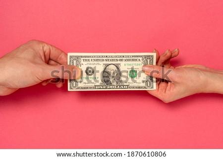Two hands are fighting over one dollar. Pulling in each direction.Two hands stretching dollar symbolizes the harsh business reality