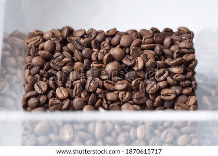 Top view on coffee beans in a transparent box on white background.