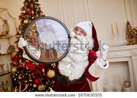 Five minutes to New year or Christmas midnight.  Happy Santa Claus shows on the clock