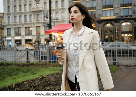 Business woman with coffee in her hands walking down the street