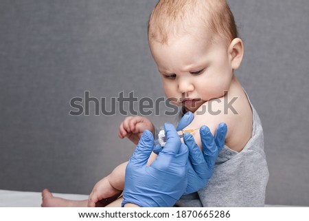 Pediatrician or nurse giving an intramuscular injection of a vaccine to arm of a baby girl during coronavirus COVID-19 pandemic Royalty-Free Stock Photo #1870665286