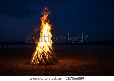 Big campfire at the river after sunset 