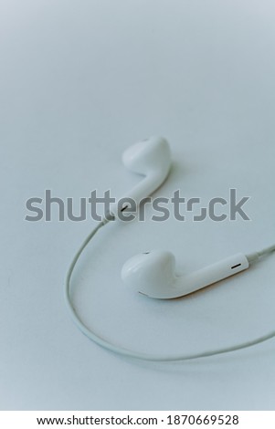 in-ear headphones are wired. White wired headphones lie on a white background. The concept of modern technologies and gadgets. Minimalism, close-up.