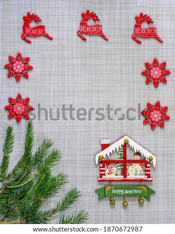 New Year's concept - a branch of a Christmas tree, a New Year's house and decor on a light background.  Macro, vertical shot. Design for postcards, place for text. Kyiv (Kiev), Ukraine, Europe.