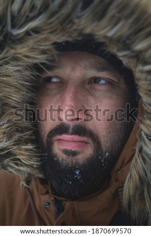 man at winter in stormy weather wearing warm fur jacket