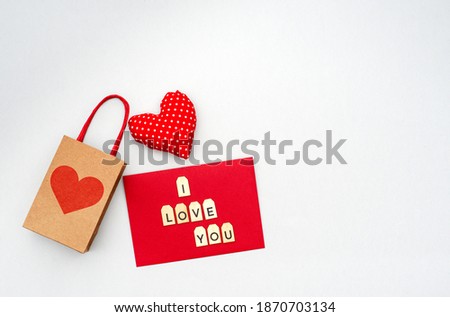 Valentines day red shape of heart with paper bag and envelop with wooden letters on grey background. Copy spase