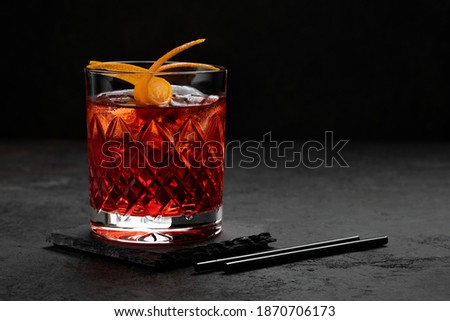 Classic Negroni Cocktail in a retro glass with ice and orange peel on a black background, space for text Royalty-Free Stock Photo #1870706173