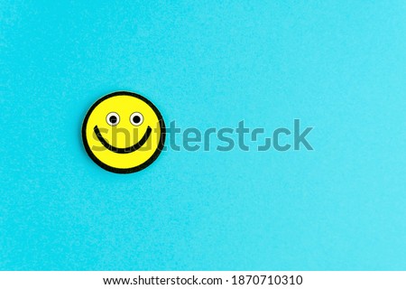 Yellow emoticon with funny eyes on bright blue background. Good day wishes. Copy space for your text