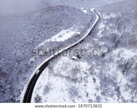 High angle aerial view drone image on the road trough the trees and forest in mountain range covered with white snow in winter day near Knjazevac in Serbia - Travel journey and vacation concept