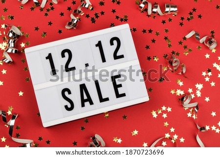 12.12 sale text on white lightbox, holiday ribbon and small stars on red background. Online shopping, singles day sale concept. Top view copy space 