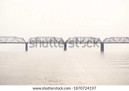 railroad truss bridge over a wide river in the morning fog