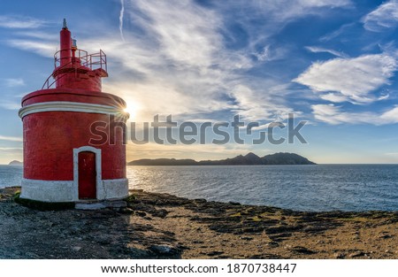 The golden sun behind the Punta Robaleira lighthouse in Galicia and the Cies Islands behind Royalty-Free Stock Photo #1870738447