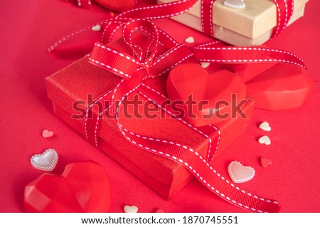 Valentine greeting card background, with  gift box festive ribbons, assorted hearts  on red table backdrop top view copy space for text.