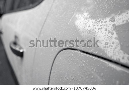 Beautiful rain drops on the car of trendy gray color. Wet car body of trendy gray color. Colou of the year concept.