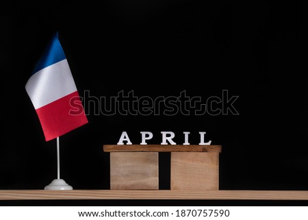 Wooden calendar of April with table French flag on black background. Holidays of France in April.