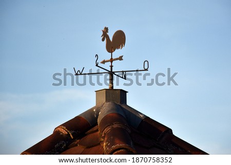 Weathercock on a house gable Royalty-Free Stock Photo #1870758352