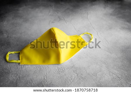 medical mask made of yellow fabric on a gray background