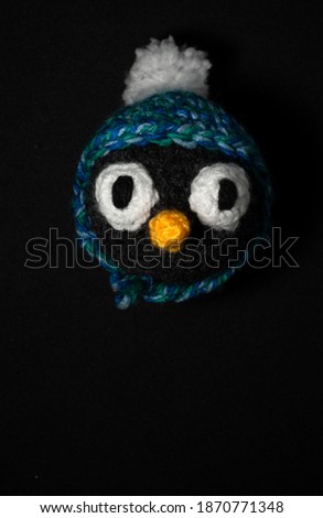 Portrait of Christmas Amigurumi penguin crocheted or knitted stuffed toy on black background