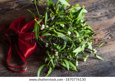 Branch of christmas mistletoe with red bow on wooden table