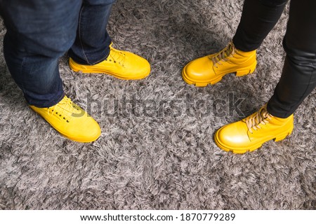 Demonstrating trendy colors 2021 - Gray and Yellow. Couple in similar clothes standing on fluffy carpet
