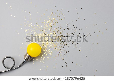 One decorative lamp on a light background with a scattering of sparkles of stars symbolizing the rays of light from the lamp. Conceptual photography.