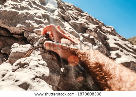 Difficult hard ascent upward - a male hand clings to a stone with his fingers - striving forward to success Royalty-Free Stock Photo #1870808308