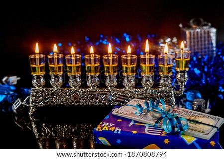 Money as a present with menorah for Hanukkah on black background. Jewish holiday tradition.