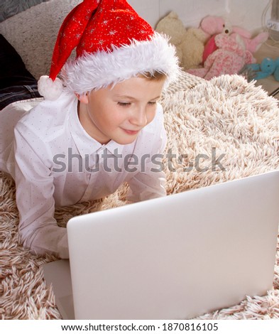 A cute little boy communicates online on a laptop, children at home during quarantine, video call, online greetings, Christmas and New Year 2021, coronavirus pandemic.
