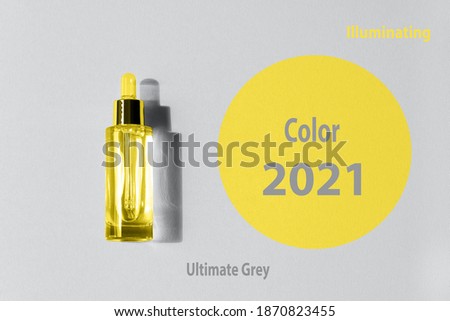 A beautiful transparent bottle with dropper cosmetic serum illuminating, yellow, ultimate, grey color background. Color year 2021, concept fashion, trendy beauty season, design spring, summer.