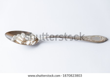 Medicine and health, treatment, pharmacy, coronavirus, pandemic, epidemic concept - layout one silver big tablespoon with different pills and capsules on a white background copy space.