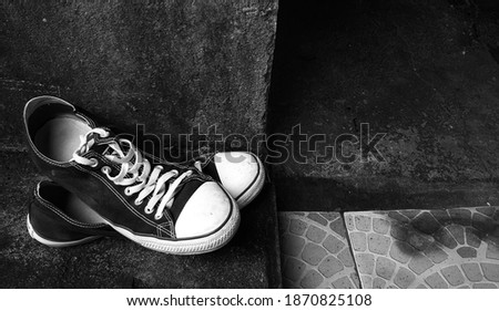 A Pair Of Sneakers Thrown On The Stone Floor, In Black And White. 
