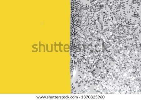 transparent liquid with silver glitter pouring over a pastel yellow background festive backdrop for your project toned colors of the year illuminating and ultimate gray