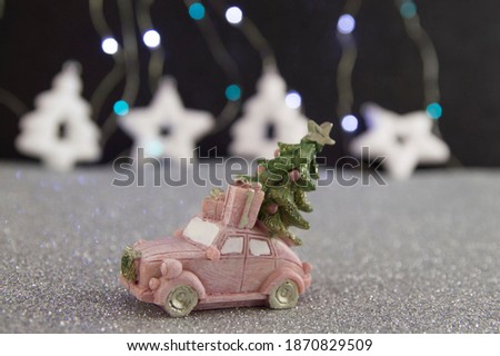 pink car carrying a christmas tree and gifts on a gray shiny background.New year.
