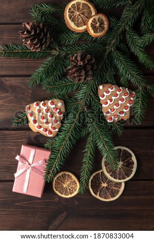 pink gift box with cones, spruce branches, cookies shaped christmas tree and dry slices of citrus on a dark wooden background. concept of new year celebration