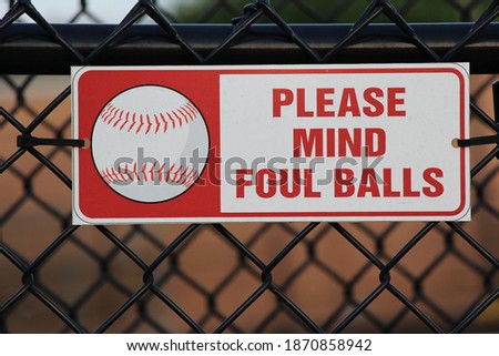 Close up of warning sign on fence reading please mind foul balls.