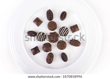 White plate filled with molded chocolates isolated over white top down view