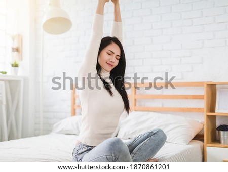 Beautiful young woman stretching and waking up in the bedroom