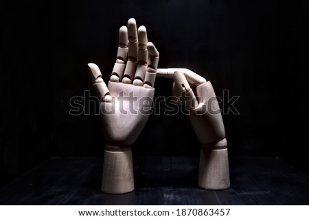 A wooden hand that is pointing while another one dodges the forefinger