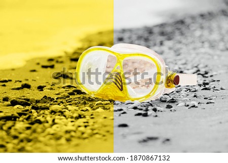 Diving mask on a two-tone background-grey and yellow.Trendy colors of the 2021.Close up photography of snorkling mask standing in the sand.Underwater diving concept.