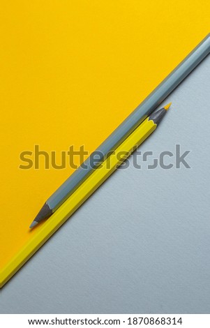 Gray and yellow pencils on a two-color background lying parallel in opposition to each other. Minimalistic banner with colors of the year 2021 - Illuminating and Ultimate Gray. 