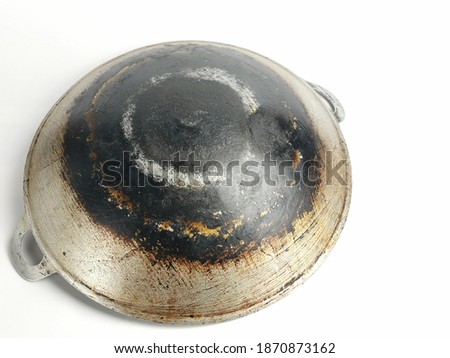 Selective focus picture with noise effect of charred and burnt base of an old used cooking wok isolated on white background.
