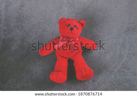 Red teddy bear with red scarf on grey background 